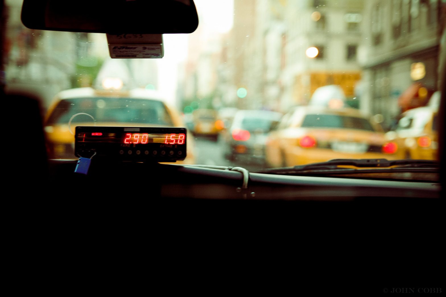 Foto da parte interna de um táxi, com a vista de uma rua movimentada na frente. Imagem ilustrativa para texto seguro para táxis e ubers.