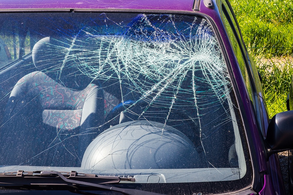 Foto do vidro de um carro vermelho quebrado. 